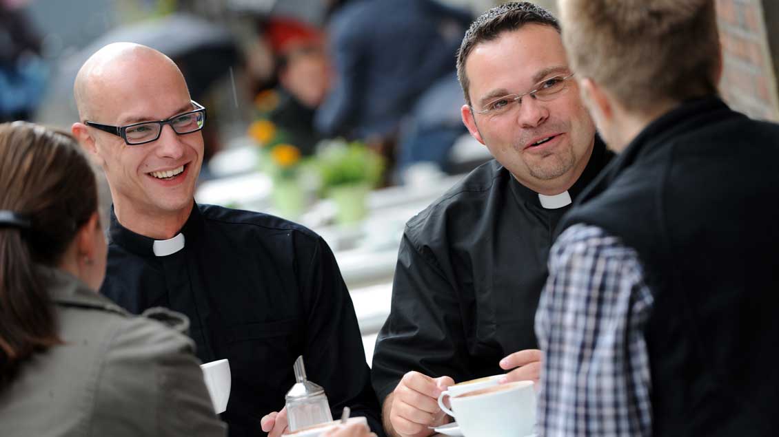 Zwei Priester im Gespräch mit zwei Frauen im Café