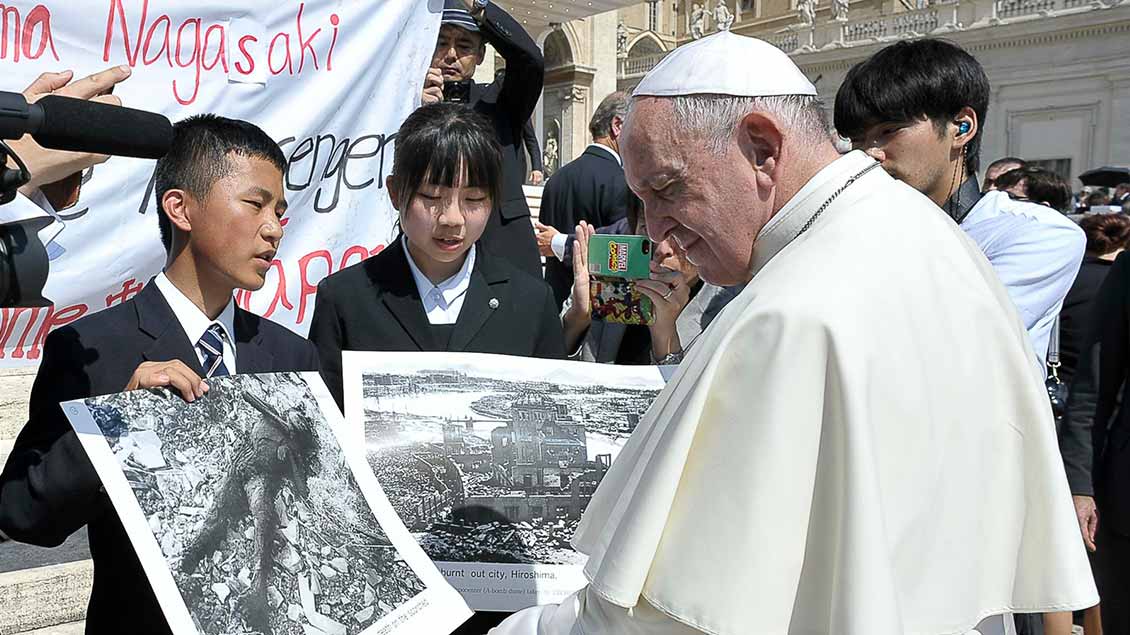 Papst Franziskus mit jungen Menschen aus Hiroshima und Nagasaki, die ihm Fotos nach den Atombombenabwürfen 1945 zeigen