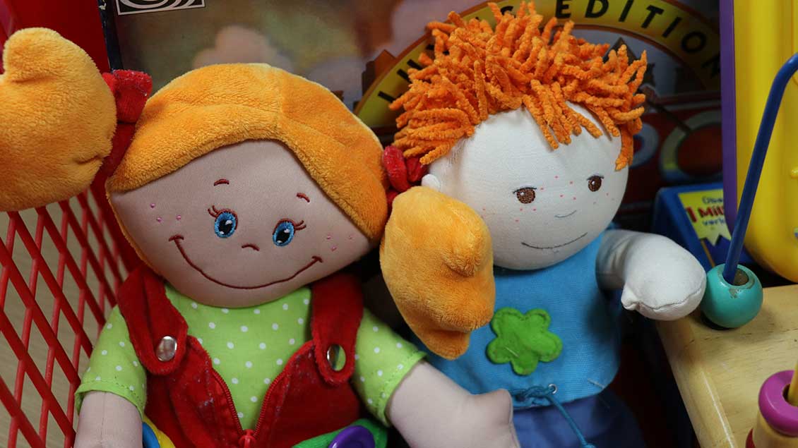 Zwei Puppen mit bunten Kleidern stehen in einem Regal zum Verkauf.