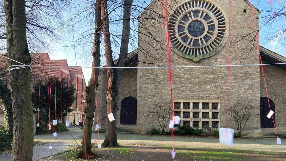 Vor der Marienkirche in Warendorf hängen die Sinnsprüche an Fäden zwischen den Bäumen.