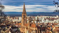 Das Freiburger Münster und die Stadt Freiburg. Am Himmel hängen dunkle Wolken