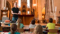 Lehrer mit Klasse in einer Kirche