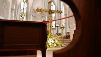 Zwischen zwei Kirchenbänken ist eine Absperrleine gespannt.