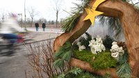 Hinter einer Krippe auf dem Krippenweg fährt ein Radfahrer vorbei.