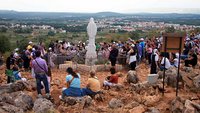 Pilger rasten an einer Statue der Muttergottes in Medjugorje.