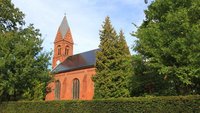 Eine Kirche im Grünen. Auf dem Dach liegen Solarzellen