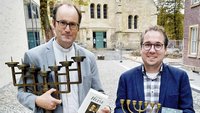 Pfarrer Markus Trautmann (links) und Florian Kübber zeigen eine Miniaturkopie der Menora, des Siebenarmigen Leuchters aus dem Jerusalemer Tempel. Die Menora ist ein klassisches Souvenir einer Pilgerfahrt nach Israel. Sie ist eines der wichtigsten Symbole des Judentums. | Foto: Patrick Hülsheger