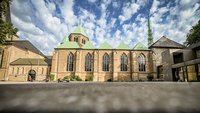 Der Essener Dom bei Sonnerschein. Der Himmel ist leicht bewölkt.