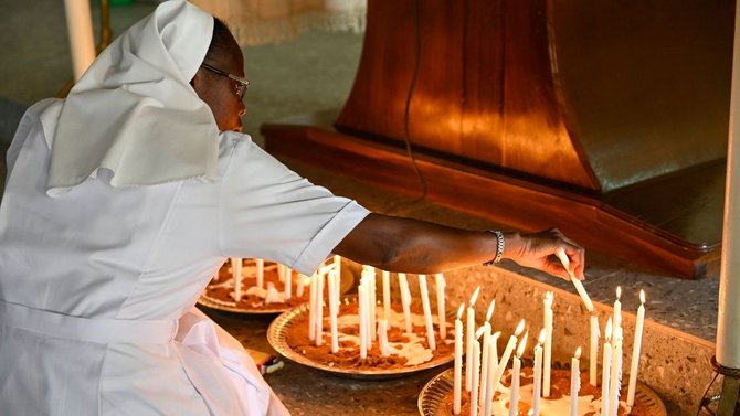 Ordensfrau zündet Kerze an