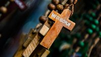 Holzkreuz an einem Rosenkranz mit der Aufschrift "Medjugorje".