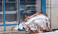 Obdachlose Person im Schlafsack vor einem Hauseingang