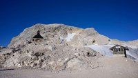 Eine Kapelle ist in einen Berg gebaut. Daneben ist ein Gletscher.