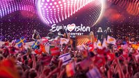 Zuschauer feiern beim ESC und schwenken Fahnen.