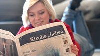 Eine junge Frau liest „Kirche+Leben“