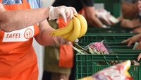 Ein Mitarbeiter der Tafel hält Bananen in der Hand.