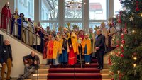 Viele Sternsinger stehen auf einer Treppe und singen. 