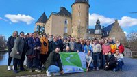 Viele junge Menschen stehen vor der Jugenburg Gemen mit der Flagge des BDKJ