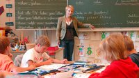 Lehrerin an der Tafel vor einer Grundschulklasse