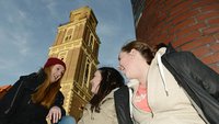 Jugendliche sitzen vor einer Kirche