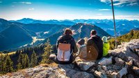 Vater, Mutter und zwei Kinder sitzen im Gebirge und machen Pause.