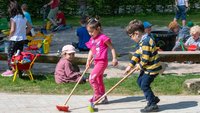 Kinder spielen mit Besen in einer Kindertageseinrichtung.