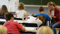 Eine Lehrerin erklärt im Unterricht Schülern etwas