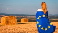 Frau mit Europa-Fahne auf einem abgteernteten Getreidefeld