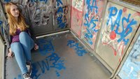 Junge Frau in Gedanken vor einem Grafiti.