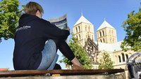 Junge Frau mit Kirche+Leben vor dem Paulusdom