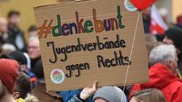 Auf einer Demonstration wird ein Schild hochgehalten auf dem "Jugendverbände gegen Rechts" steht.