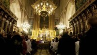 Viele Menschen in einem dunklen Kirchenraum in Polen.