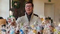 Wolfgang Pietrusiak hält Tüten mit Weihnachtshäuschen in der Hand.