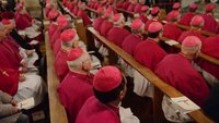 Bischöfe sitzen nebeneinander in einer Kirchenbank.