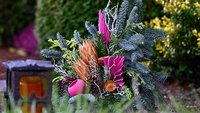 Gesteck und Grablicht auf einem Friedhof