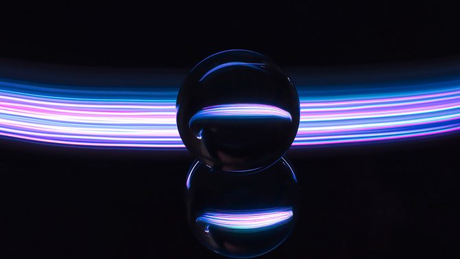 Dunkle Glaskugel vor einem bunten Lichtstreifen