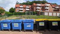 Wertstofftonnen vor einem kleinen Spielplatz