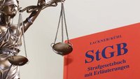 Statue Justitia und ein Strafgesetzbuch