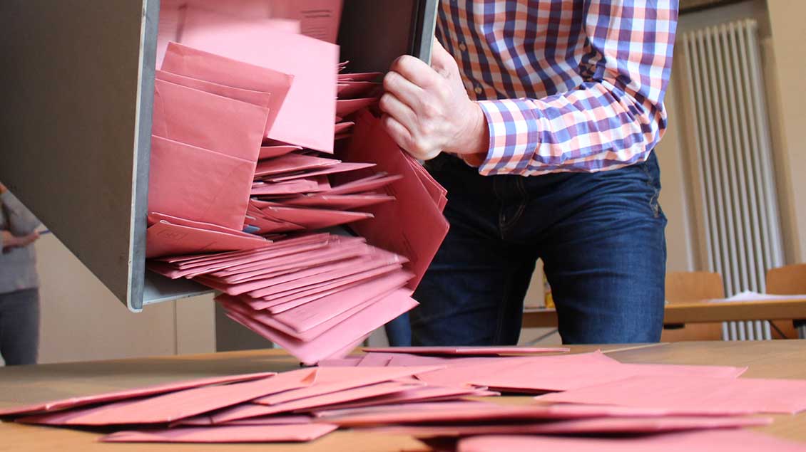Briefwahlumschläge werden aus der Wahlurne auf dem Tisch entleert.