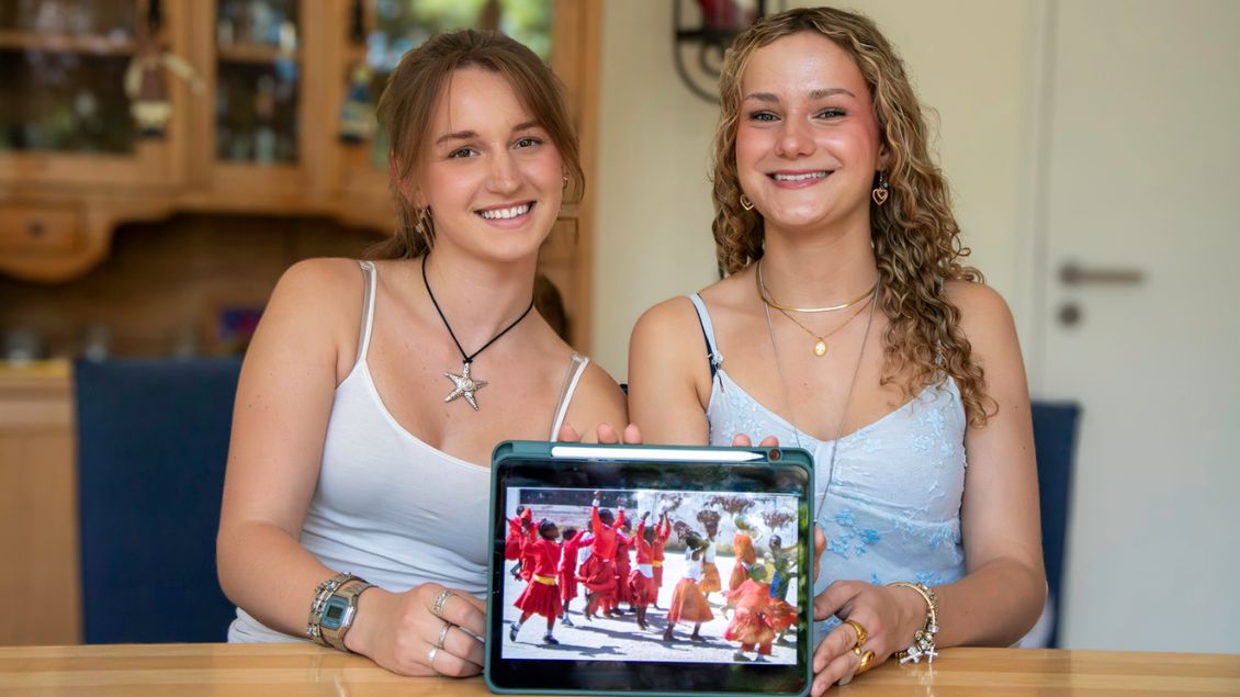 Zwei junge frauen halten ein Tablet in die Kamera.