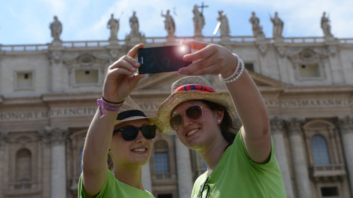 Zwei junge Menschen machen ein Selfie vor dem Petersdom.