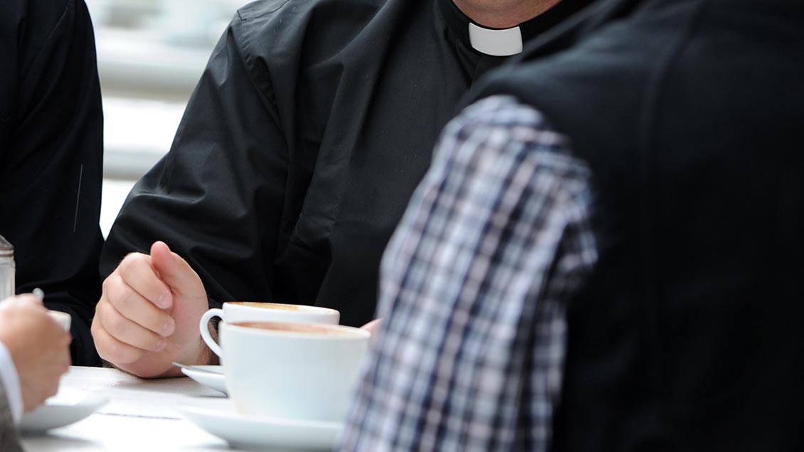 Priester im Gespräch im Café