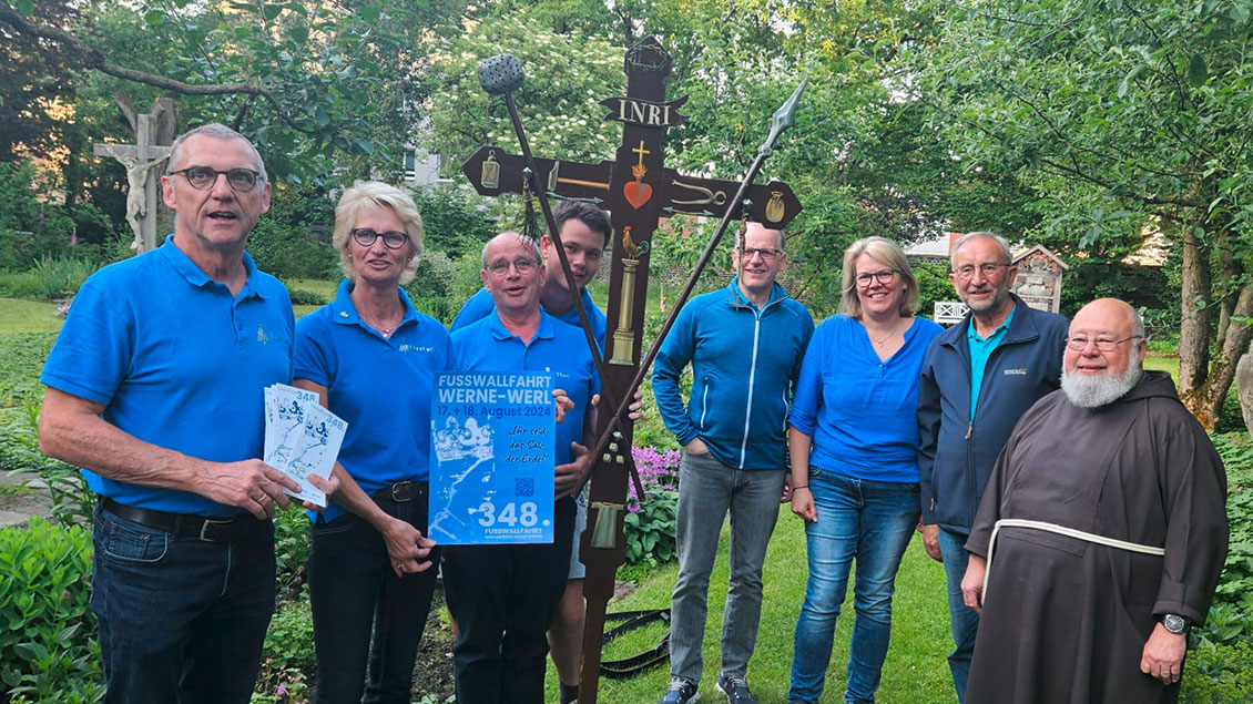 Mitglieder des Wallfahrtsausschuss Werne-Werl um Wallfahrtsleiter Klemens Pieper (links) und Kapuziner-Pater Norbert Schlenker (rechts) zeigen das Wallfahrtskreuz.