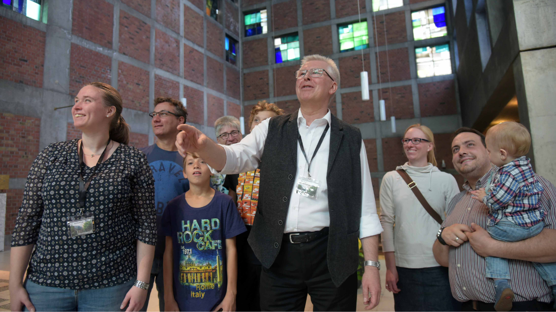 Menschen schauen beeidruckt an die Decke einer Kirche.