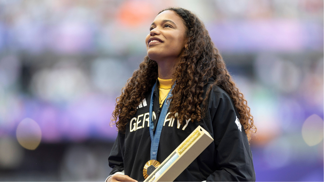 Yemisi Ogunleye trägt eine Goldmedaille und richtet den Blick nach oben.