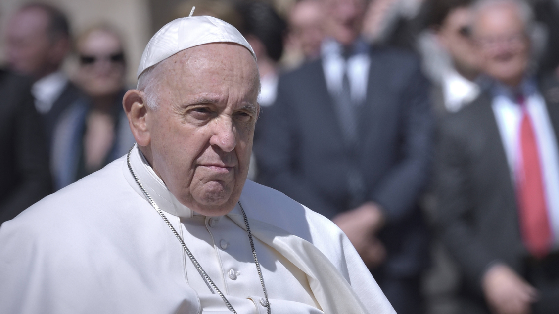 Papst Franziskus sitzt und schaut ernst.